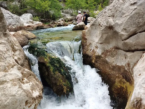 Akarsuyun kayalar arasından akarak döküldüğü huzur verici doğal manzara.