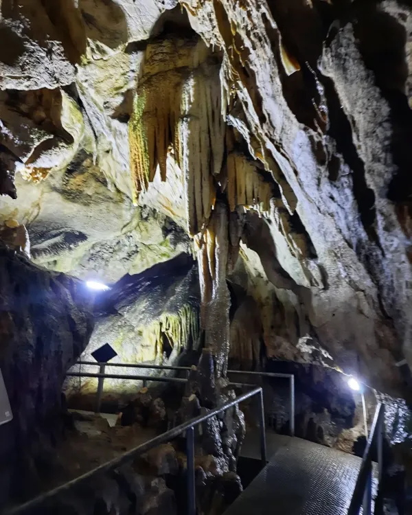 Mağara iç mekanında sarkıtlar, dikitler ve metal yürüyüş yolu görünmekte.