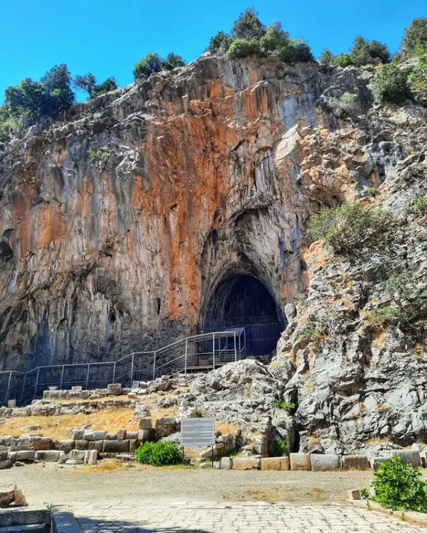Büyük kaya kütlesi önünde demir parmaklıkla korunan mağara girişi