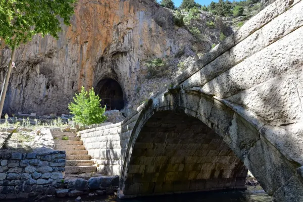 Taş köprü, su kenarı ve karanlık grotto ile doğal alan görüntüsü