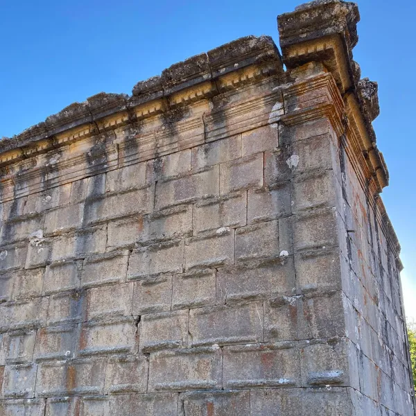 Tarihi yapının taş duvarları ve detaylı taç sırası net mavi gökyüzü ile gözler önünde.