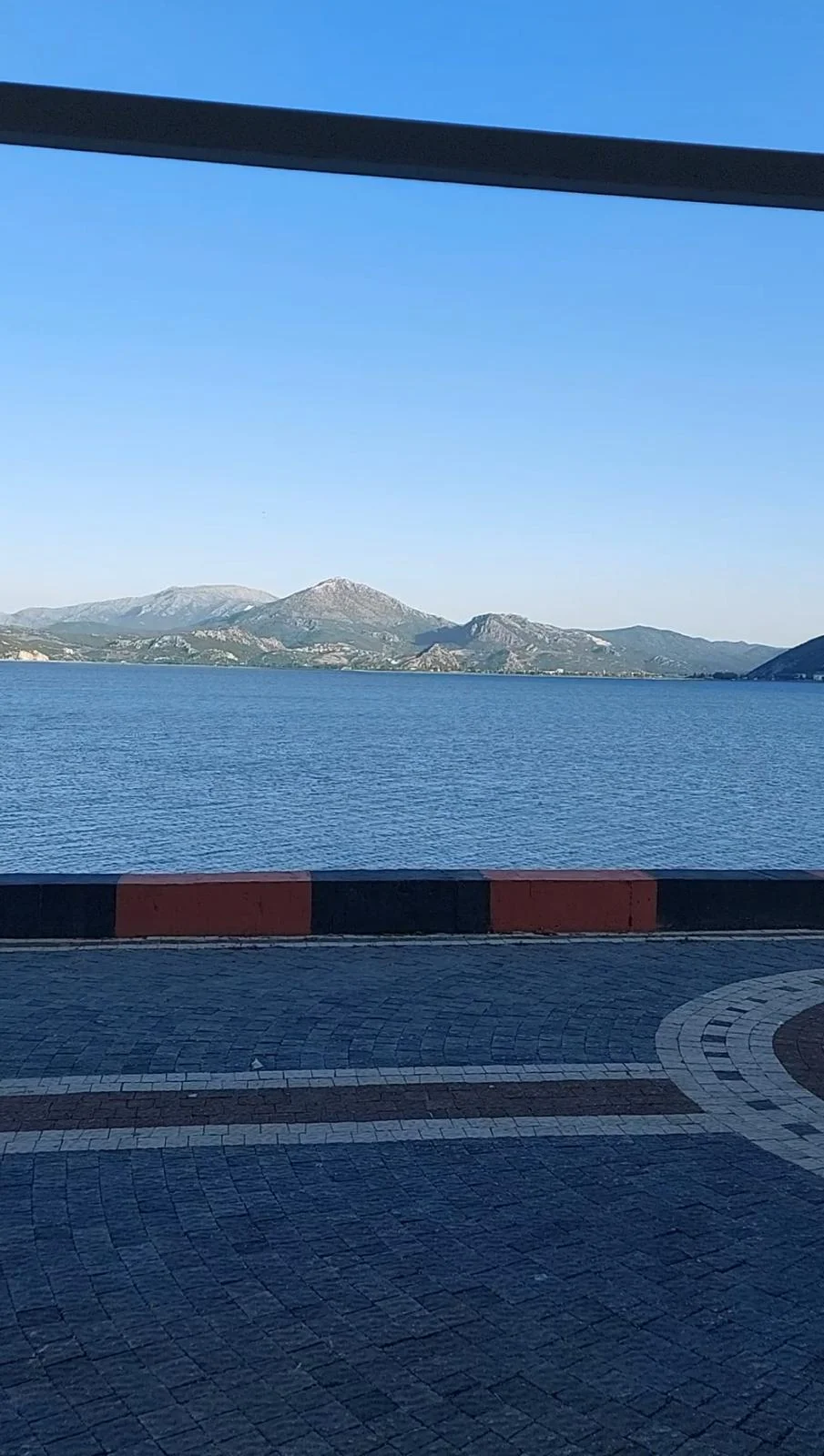 Eğirdir Gölü'nde mavi su, dağ silueti ve yeşil alanlar görünmekte.