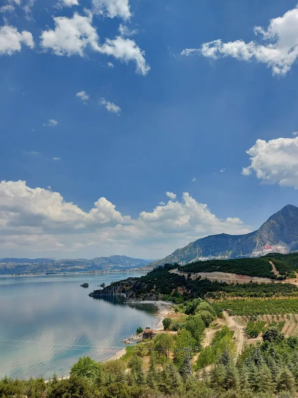 Sakin bir günde Eğirdir Gölü'nün berrak suyu ve çevresindeki yeşil ağaçlar.