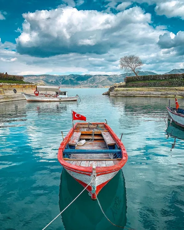 Türk bayrağı dalgalanan tekne, hafif dalgalı su ve dağ manzarası