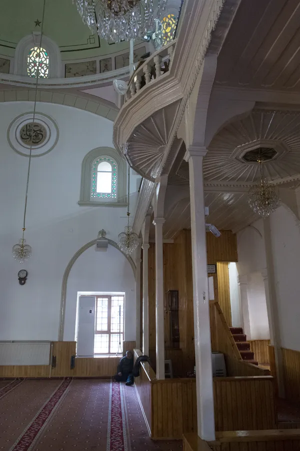 Aydınlatılmış Firdevs Bey Camii iç mekanı, süslü tavan ve avizelerle göz alıyor.