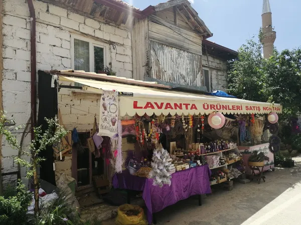 Lavanta ürünleriyle dolu tezgah, arka planda taş yapı ve cami minaresi görünümünde.