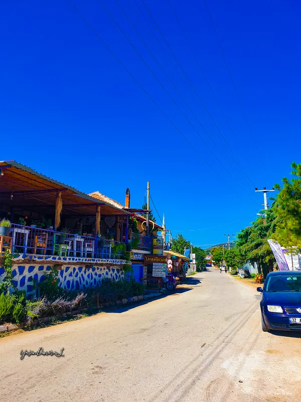 Kuyucak Köyü'nde restoranlar ve dükkanlarla çevrili huzurlu bir sokak görüntüsü.