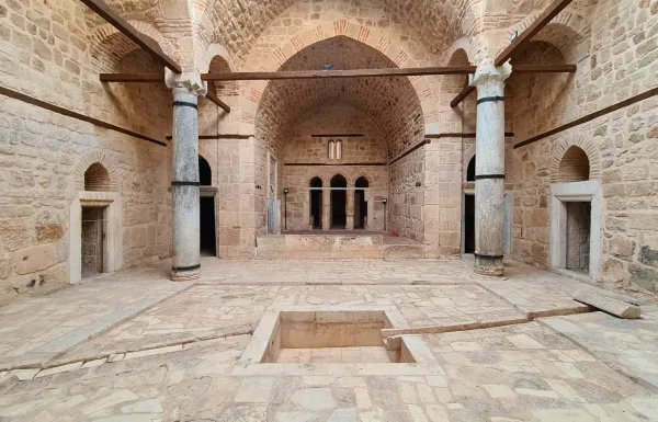 Eski bir yapının iç mekanı, taş duvarlar ve yüksek kemerli tavan ile dikkat çekiyor.