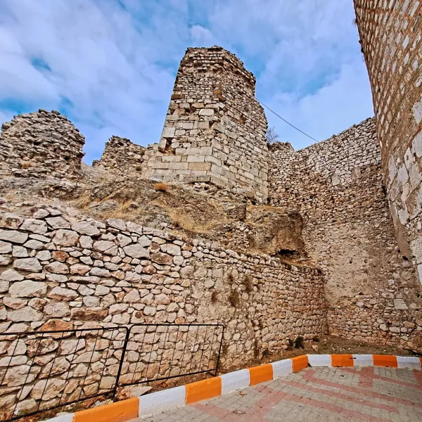 Eğirdir Kalesi'nde yıkılmış kule ve taş duvarlar, açık mavi gökyüzü ile birleşiyor.