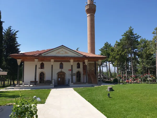 Beyaz duvarları ve kırmızı çatısıyla Ertokuş Medresesi, yeşil alan ve ağaçlarla çevrili.