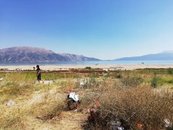 Yalvaç Taşevi Plajı'nda yürüyen bir kişi ve arka planda dağlarla çevrili sahil manzarası