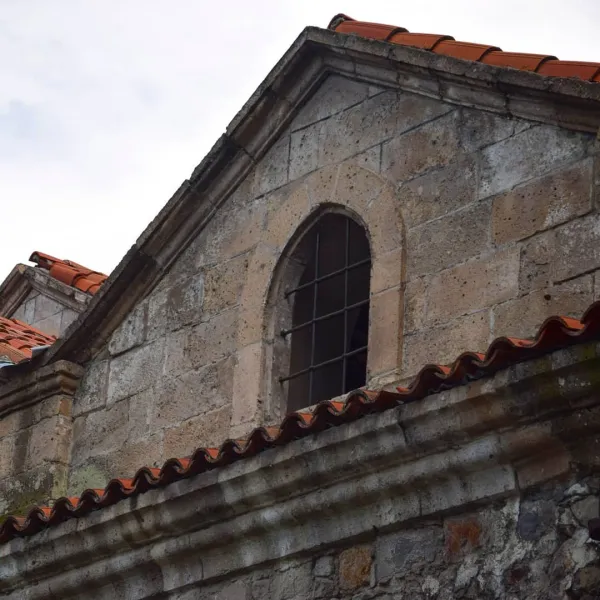 Eski taş yapının üst kısmı ve kırmızı kiremitli çatısı görünmekte.