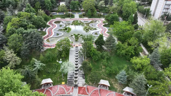 Yeşil park alanı, modern su yolları ve gölet ile çevrili, huzurlu bir ortam.