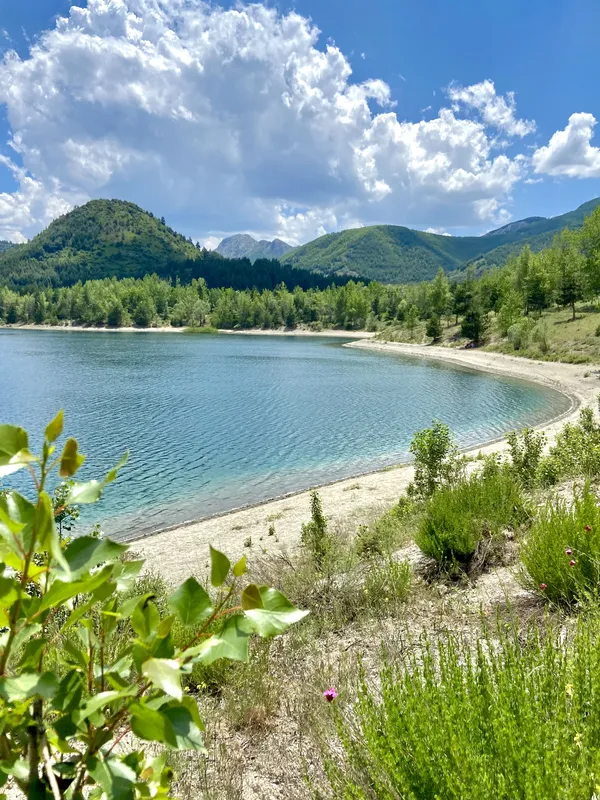 Huzur verici göl manzarası ve çevresindeki yeşil dağlar.