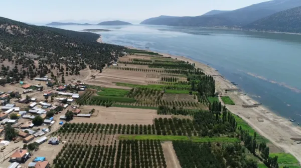 Tarım arazisi, dağlar ve su kenarında küçük yerleşim alanı görünümü