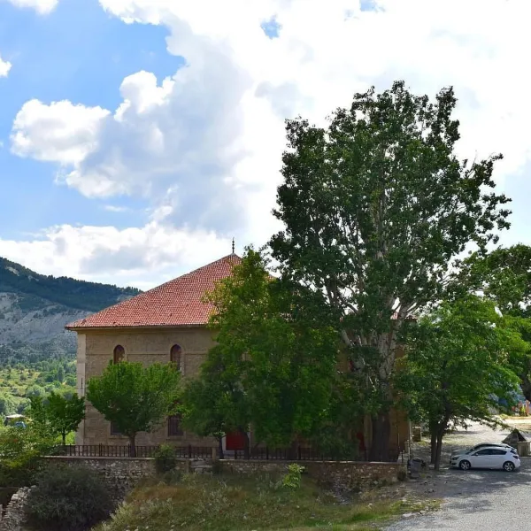 Yeşil ağaçlarla çevrili Uluborlu Kalesi'nin görünümü, arka planda dağlar ve beyaz bulutlar var.