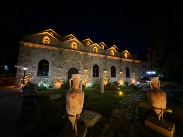 Gece aydınlatmasıyla öne çıkan Aya Payana Kilisesi, antik amforalar ve yeşil alanlarla çevrili.