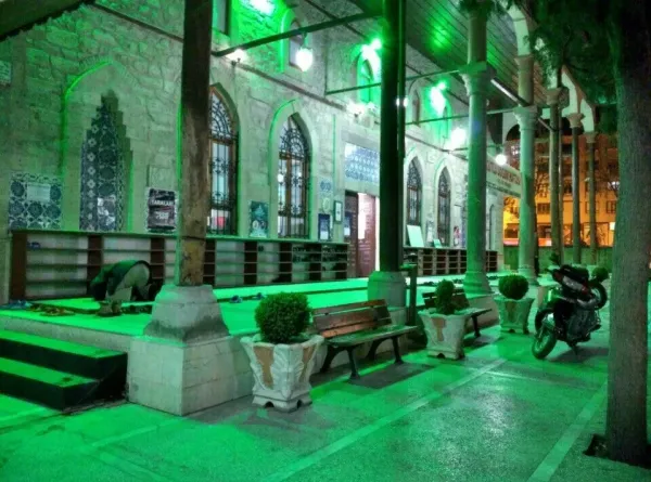 Geniş bir alanda taş duvarlar, geleneksel pencereler ve saksılarda bitkilerle huzurlu bir ortam.