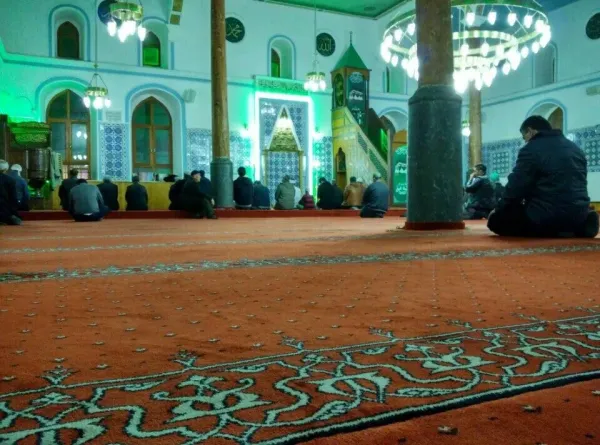 Abdi Paşa Peygamber Camii iç mekanında dua eden insanlar, mavi çiniler ve büyük sütunlar.