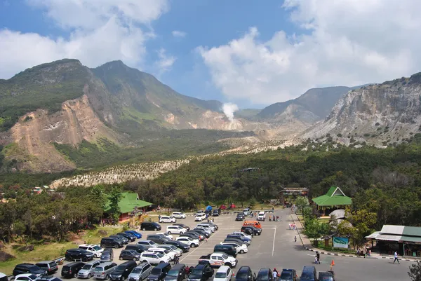 Yeşil ağaçlarla kaplı alanda, dağların arasında otopark ve volkanik alan görünmekte.