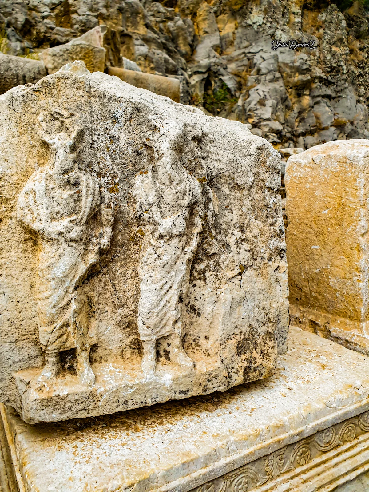 Eski bir taş mekanda, elbise giymiş iki figür ve doğal taş yapıları