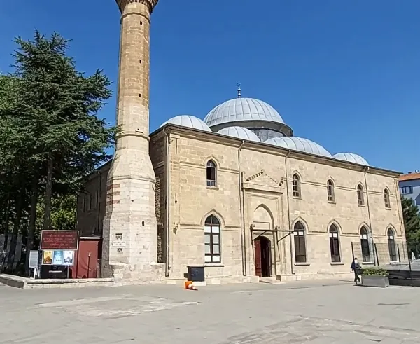 Açık tonlarda taşlarla inşa edilmiş, belirgin minaresi ve kubbeleri olan tarihi cami.