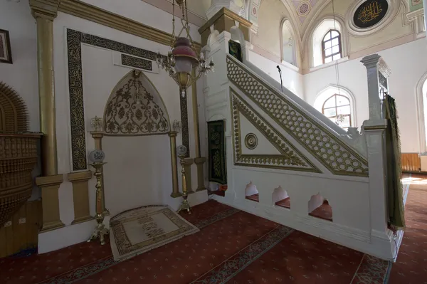Kutlu Bey Camii iç mekanında zarif mihrab ve ahşap minber görünmektedir.