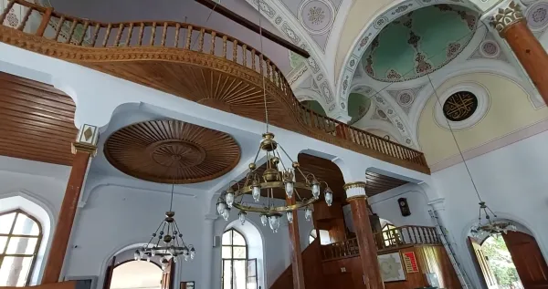 Ahşap trabzanlarla çevrili galeri ve zarif desenlere sahip tavan görünümü.