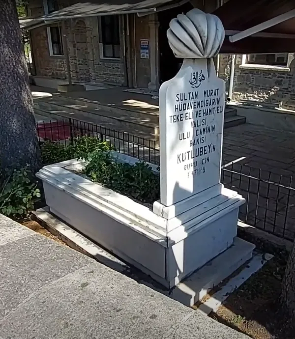 Beyaz mezar taşı, deniz kabuğu figürüyle ve yazıtlarıyla dikkat çekiyor.