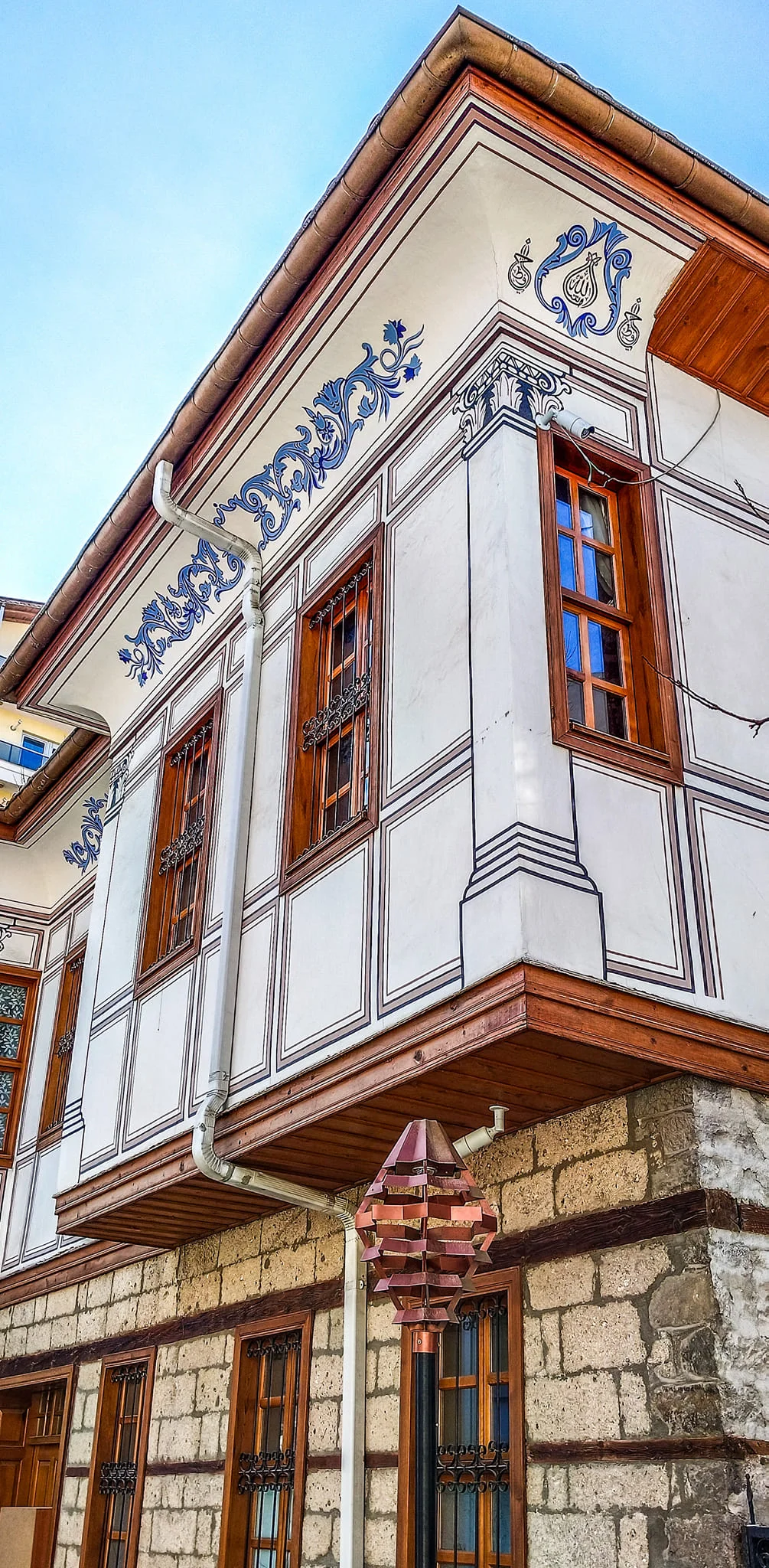 Beyaz sıvanmış duvarları ve ahşap pencereleriyle tarihi bir Isparta evi.