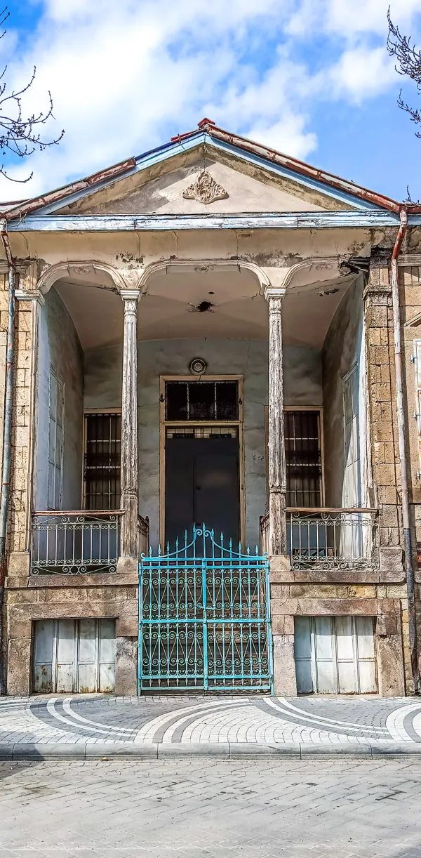 Tarihi bir bina, süslü detaylar, zarif sütunlar ve mavi çatı ile göz alıyor.