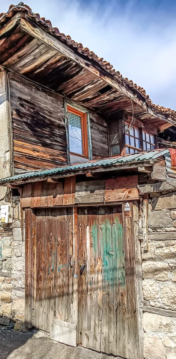 Ahşap ve taş detaylarıyla süslü tarihi Isparta evi, açık pencere ve eski kapıyla dikkat çekiyor.