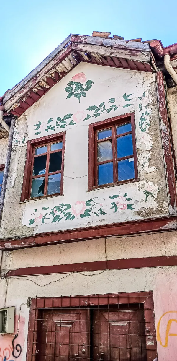 Eski bir Isparta evinin beyaz-gri dış cephesi ve ahşap çatısı