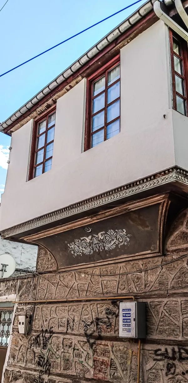 Beyaz duvarlar, büyük pencereler ve taş zemin ile tarihi Isparta evi.