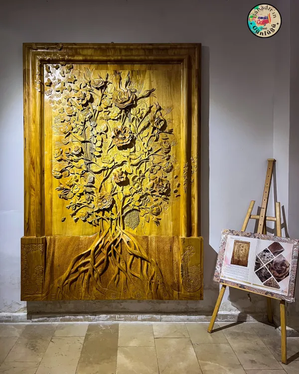 Büyük ağaç motifi etrafında detaylı çiçek ve yapraklarla bezenmiş ahşap kabartma eseri