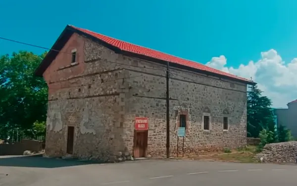 Taş yapılı Aya Stefanos Kilisesi, kırmızı kiremit çatısı ve yeşil ağaçlarla çevrili.