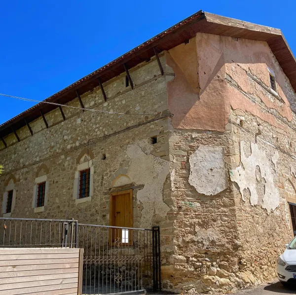 Taş yapının köşesi, ahşap çatı, altıgen pencereler ve mavi gökyüzü