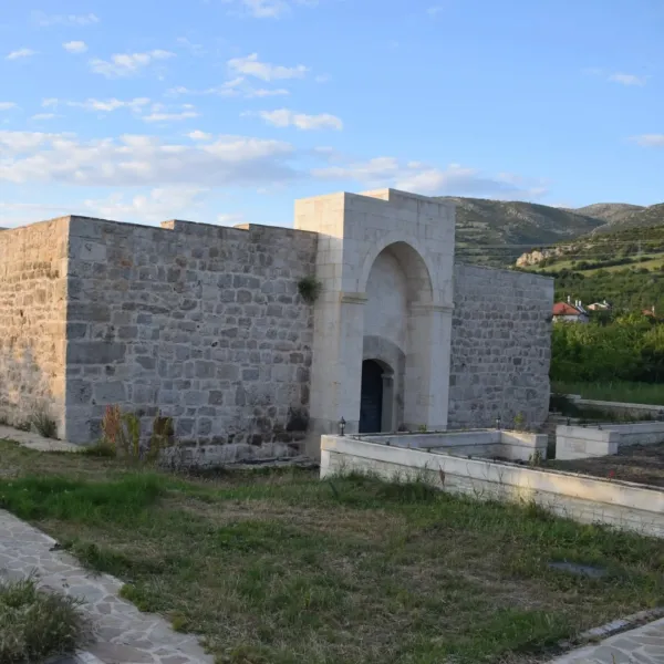 Taş yapılarla inşa edilmiş tarihi Ertokuş Hanı, çevresinde yeşil dağlar ve mavi gökyüzüyle dikkat çekiyor.