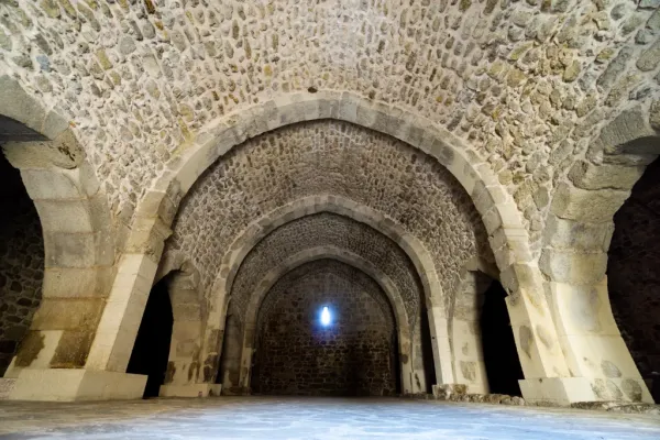 Taşlardan yapılmış geniş iç mekân, yüksek kemerler ve doğal ışık ile aydınlatılan atmosfer.