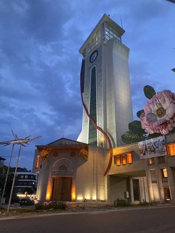 Modern saat kulesi ve geleneksel mimari tarzda müze binası ön planda.