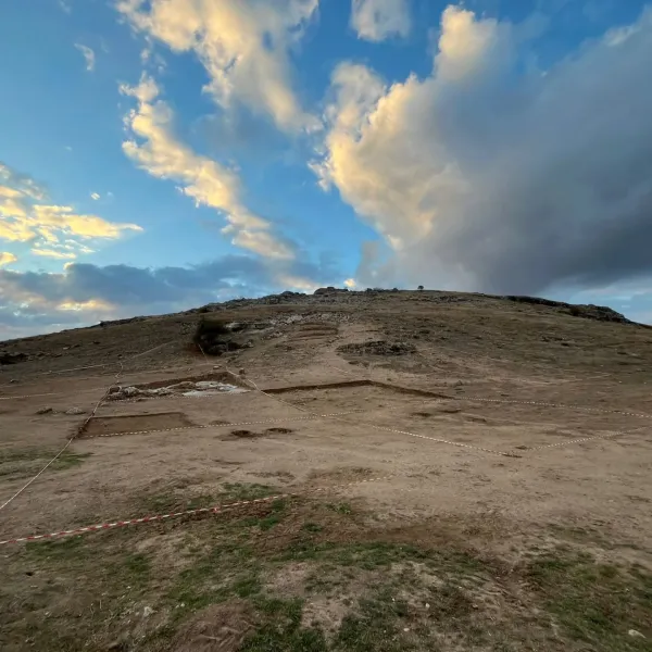 Geniş oval alanda kayalık bir tepe ve arkeolojik kazı izleri.