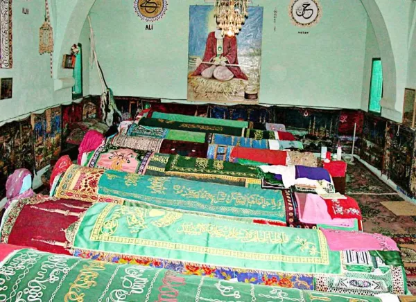 Farklı renklerde örtülerle kaplı mezarların bulunduğu sakin bir iç mekan