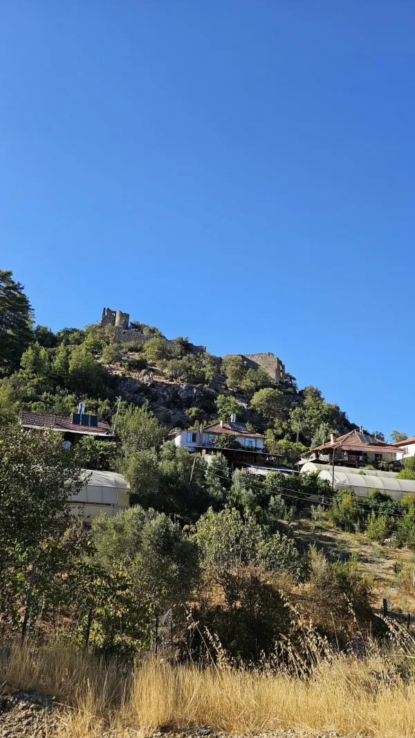 Yüksek tepe üzerindeki kale kalıntıları ve çevresindeki yeşil alanlar