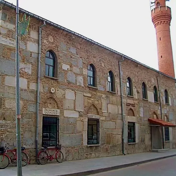 Taş duvarlardan oluşan Devlethan Camii, ön planda iki bisiklet ve minaresiyle dikkat çekiyor.