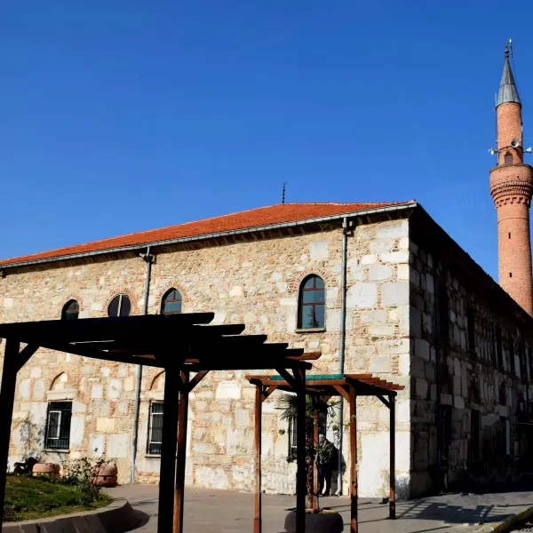 Tarihi Devlethan Camii'nin taş dış cephesi ve yüksek minaresi görünmekte.