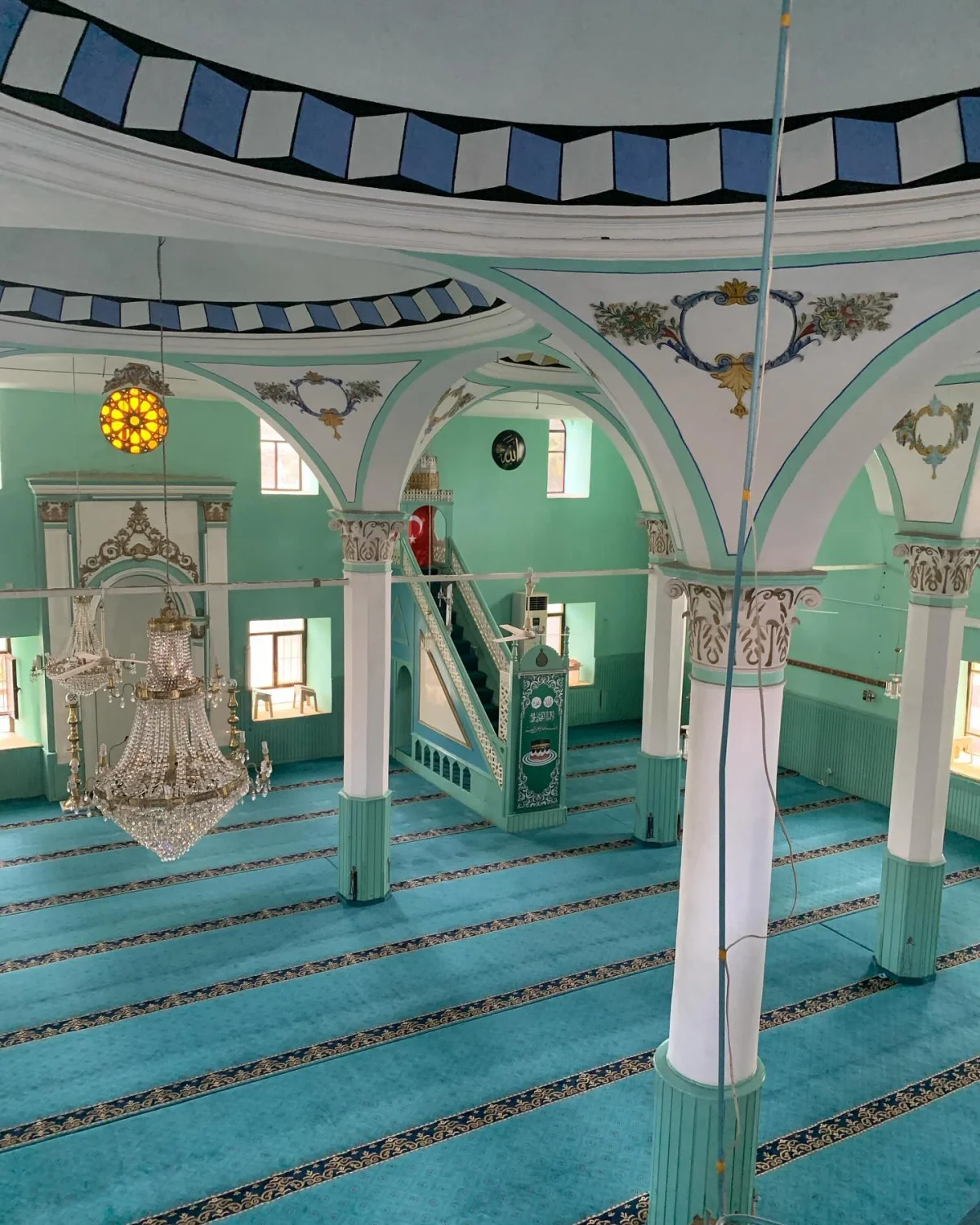 Zarif İç Mekân - Yeşil Duvarlar ve Mavi Desenli Tavan Açık yeşil duvarlar ve mavi desenli tavan ile iç mekânı gösteren geniş bir cami.