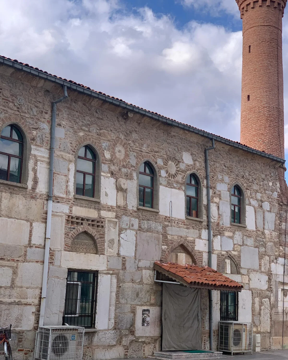 Devlethan Camii'nin Taş ve Tuğla Cephesi - Tarihi Güzellikler! Tarihi Devlethan Camii'nin taş ve tuğla dış cephesi, yeşil kemerli pencereleri ve yüksek minaresiyle dikkat çekiyor.