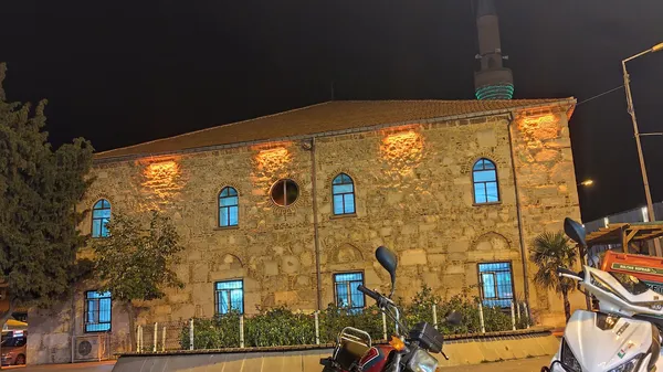 Taş bir bina, mavi camlı pencereler ve canlı gece atmosferiyle.