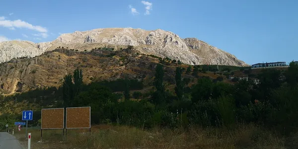 Yeşil alan, dağ manzarası ve otel yapısını içeren açık hava görüntüsü.