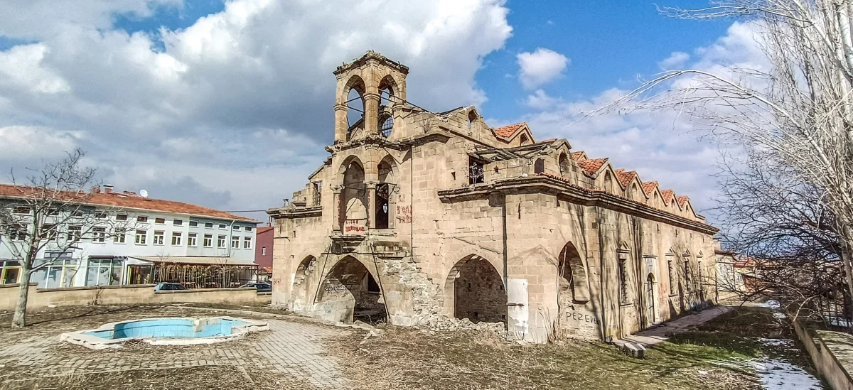 Tarihi Aya Ishotya Kilisesi'nin hasar görmüş taş duvarları ve kemerli pencereleri görünmekte.